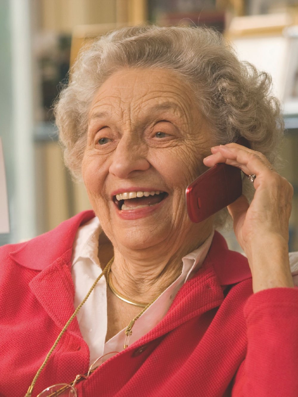 Seniorin im roten Oberteil telefoniert und lacht